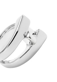 Anillo de plata con un diseño moderno y escultórico, con superficies lisas y pulidas y formas angulares. Destaca por su textura reflectante.