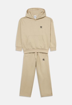 Beige Adidas hoodie and matching sweatpants set with kangaroo pocket and black Adidas trefoil logos on chest and thigh.
