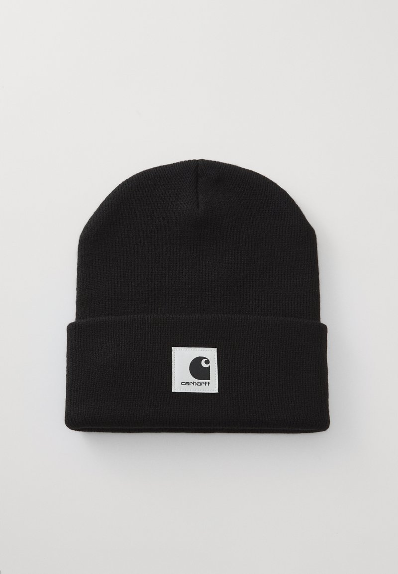 Black knitted beanie with a folded cuff. Features a square white label with a black logo. Made from soft, textured material.