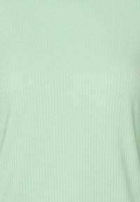 Mátově zelený pruhovaný top vyrobený z měkké tkaniny. Disponuje elastickou texturou a přiléhavým střihem, který zdůrazňuje hladký a čistý vzhled.