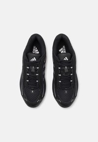 Black athletic shoes with mesh and synthetic upper, rounded toe, lace-up closure, and reflective accents on the sides.