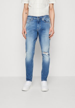 Vaqueros de denim azul claro con corte ajustado, que presentan detalles desgastados en las rodillas, diseño clásico de cinco bolsillos y cierre de cremallera.
