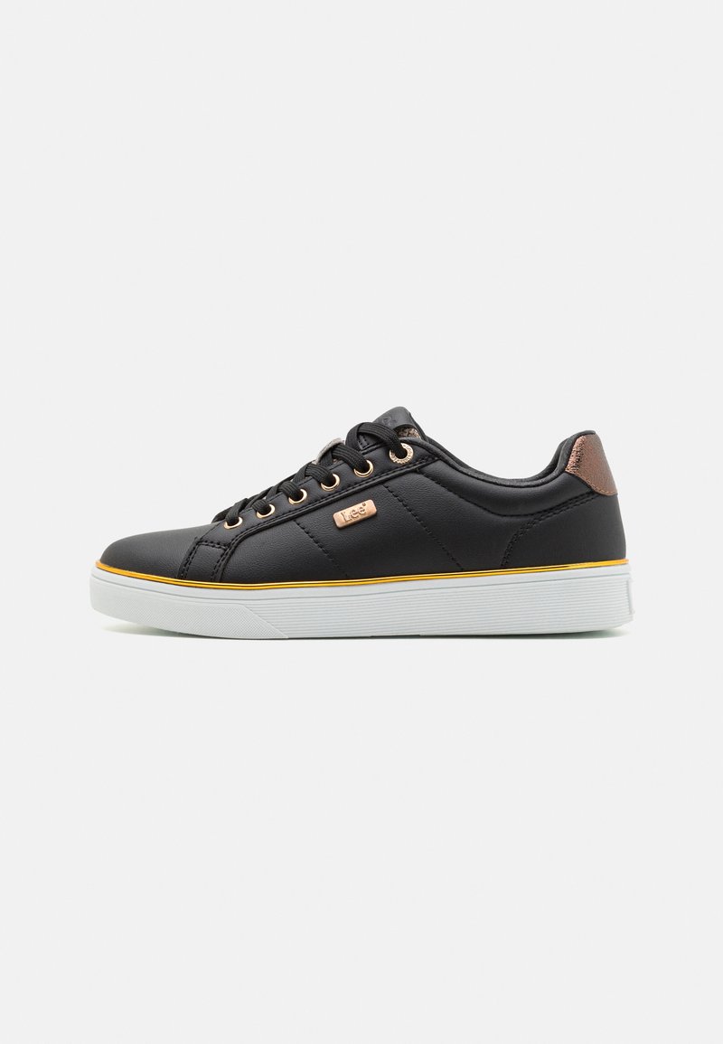 Black sneakers with a smooth synthetic upper, gold eyelets, a brown heel accent, white rubber sole, and a yellow stripe along the sole.