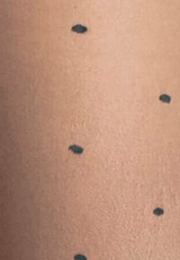 Beiger Stoff mit glatter Textur, der mit verstreuten dunkelblauen Punkten in gleichmäßigen Abständen versehen ist, was ein gemustertes Erscheinungsbild erzeugt.