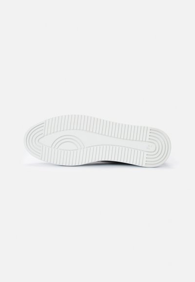 Fehér sneaker talp, amely texturált, barázdált mintával, lekerekített élekkel és tartós gumiból készült.