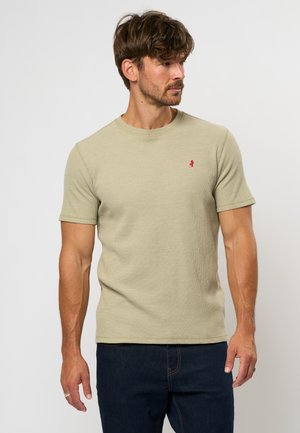 Tricou de culoare verde deschis, cu manșete scurte, fabricat dintr-un material texturat, având un mic logo roșu pe piept. Gât rotund, formă ajustată.