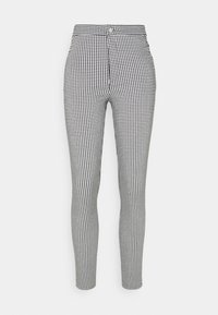 Vysoké úzké kalhoty s černobílým houndstooth vzorem, které mají zapínání na knoflík a zip vpředu.