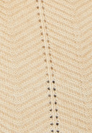 Tessuto di maglia beige con un motivo a spina di pesce, caratterizzato da una fine trama e sottili macchie scure lungo la cucitura centrale.