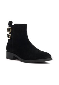 Black suede ankle boot with a rounded toe, low block heel, and two gold buckle accents on the side. Smooth textured surface.
