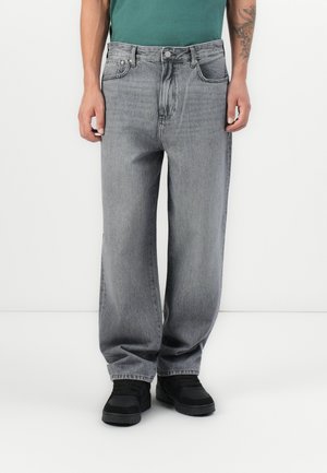 Gray denim jeans with a relaxed fit, featuring a button closure, five pockets, and a slightly distressed texture. Paired with black shoes.