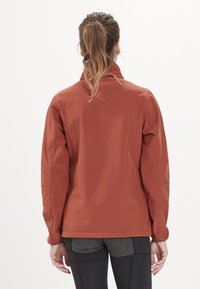 Röd, mjuk skaljacka med hög krage och långa ärmar. Har texturerade detaljer på axlarna och en strömlinjeformad passform.