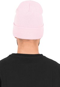 Rosa strikket lue med brettkant, laget av mykt, elastisk materiale. Har en avrundet topp og minimale søm detaljer.