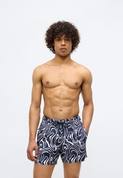 Peldbikses ar tumši zilu un baltu viļņotu rakstu, izgatavotas no viegla auduma. Iekļauj elastīgu jostasvietu un saites detaļu.