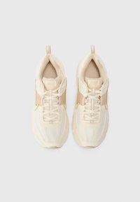 Bežni Nike športni copati z mrežno zasnovo, oblazinjenim jezikom, odsevnimi detajli in teksturiranim podplatom. Imajo vezalke in zanke na peti.