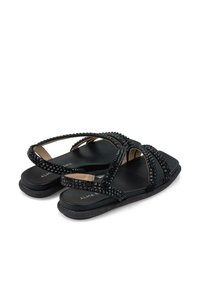 Zwarte sandalen met meerdere kruislings overlappende banden versierd met zwarte rhinestenen, met een platte zool en een minimalistisch ontwerp.