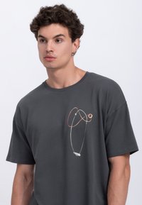 Grijze katoenen t-shirt met een kleurrijk abstract printontwerp op de voorkant. Korte mouwen en een relaxte pasvorm.