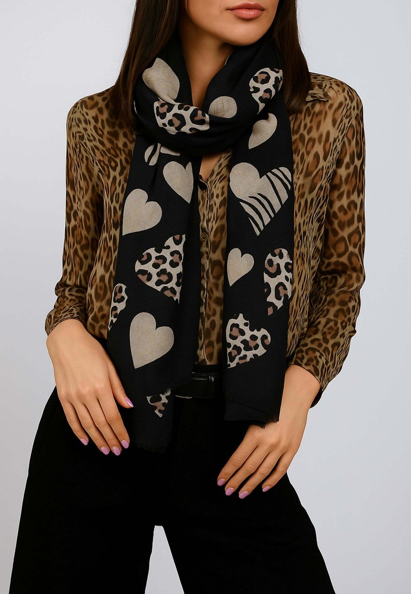 Sciarpa nera con grandi cuori beige e motivi leopardati, realizzata in morbido tessuto con bordi frangiati.