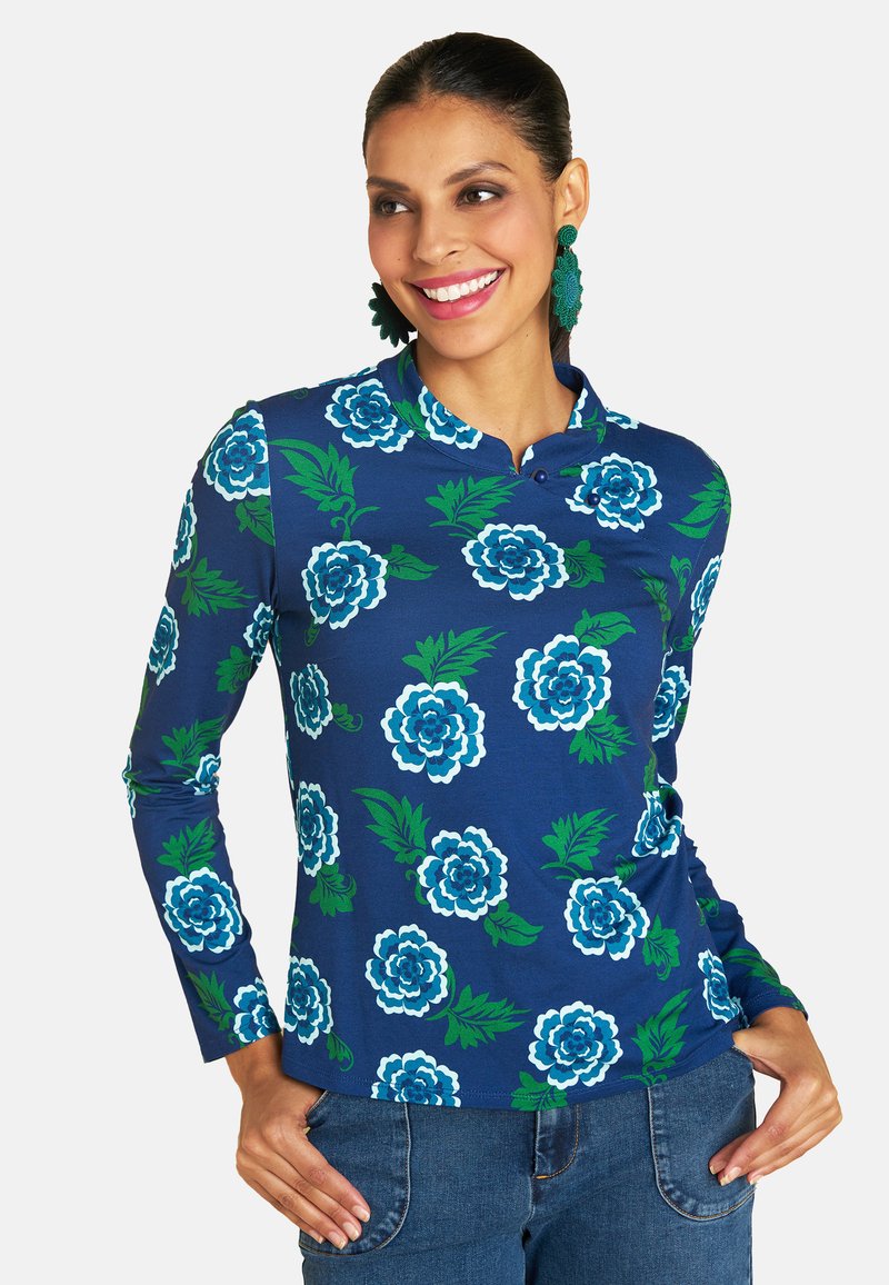 Blue long-sleeve shirt with white and teal floral patterns, featuring a henley collar and denim jeans, displaying a vibrant design.