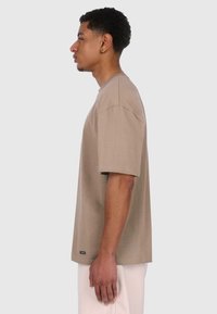 Brun kortærmet t-shirt lavet af bomuld, med rund hals og en afslappet pasform, samt et lille mærke i bunden.