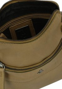Borsa in pelle marrone con chiusura zip, caratterizzata da una texture liscia e un interno nero a contrasto. Include un’etichetta con il marchio e dettagli in metallo.