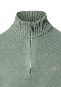Grüner, gerippter Strickpullover mit einem halbhohen Reißverschlusskragen und silbernem Reißverschluss. Mit kleinem Logo auf der Brust. Weiche Textur.