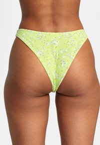 Green floral bikini bottom, ribbed texture, high-cut design, featuring small white and orange flowers against a light green background.