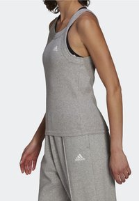 Débardeur de sport gris avec larges emmanchures, encolure arrondie et logo embossé. Confectionné en tissu doux et extensible.