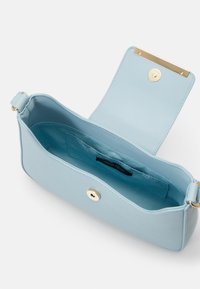 Sac bandoulière rectangulaire bleu clair avec fermeture magnétique, petite poche intérieure et ferrures dorées, rabat ouvert pour montrer l'intérieur.