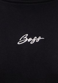 Μαύρο φούτερ με λευκό κεντητό λογότυπο "Boss" στην περιοχή του στήθους, κατασκευασμένο από απαλό ύφασμα με λεία υφή.