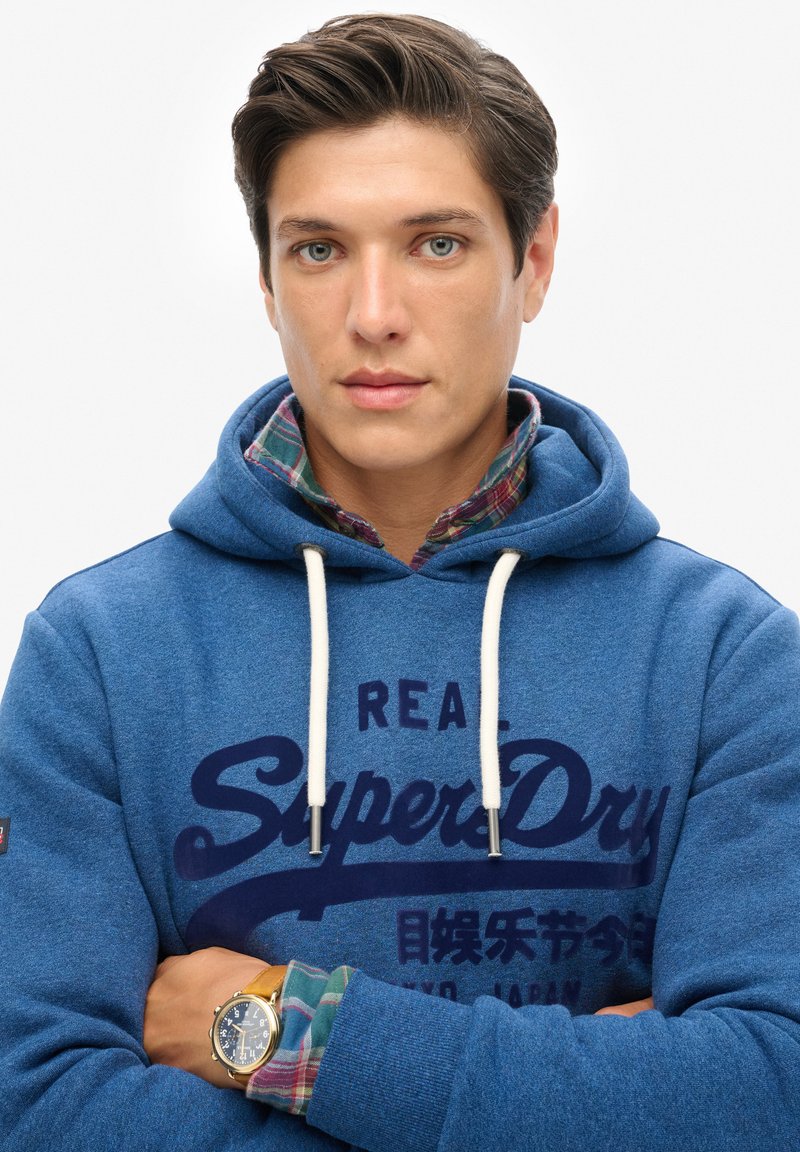Doudoune à Capuche Superdry Bleu Marine pour homme Doudoune à Capuche Superdry Bleu Marine pour homme