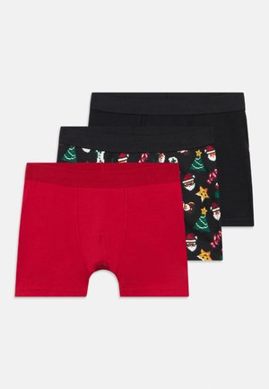 Tre paia di boxer: uno rosso, uno nero uniforme e uno nero con motivi natalizi colorati che includono alberi e Babbo Natale.