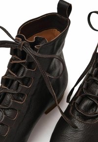 Scarpe ankle in pelle nera con lacci frontali e punta rotonda su uno sfondo bianco.