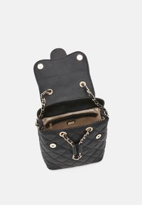 Bolso tote negro acolchado con una textura suave, herrajes en tono dorado, correas de cadena y un interior espacioso que cuenta con un bolsillo con cremallera.