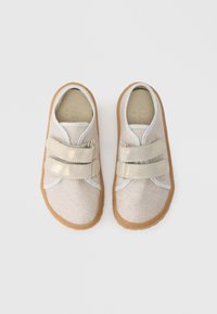 Velcro closure shoes with a light beige woven upper, silver accents, and a rubber tan sole, featuring a rounded toe and padded collar.