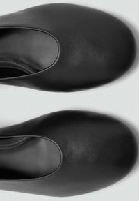 Scarpe in pelle nera con finitura liscia, punta arrotondata e ampia apertura lungo il lato superiore. Semplici, senza hardware o dettagli notevoli.
