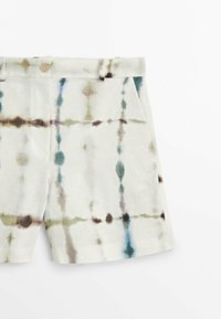 Shorts en lin à base crème avec un motif tie-dye en nuances de vert, bleu, marron et gris ; poches avant et fermeture par boutons.