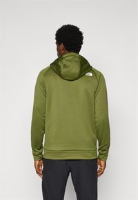 Olijfgroene hoodie met een zachte textuur, met een logo op de achterkant en een geribbelde zoom. Eenvoudig ontwerp met een relaxte pasvorm.