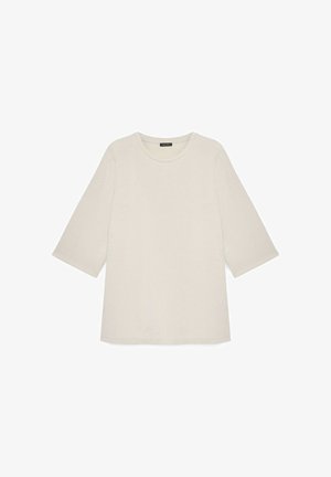 Jasnobeżowy krótki top z okrągłym dekoltem, ozdobiony subtelnym, kwiatowym wzorem wytłaczanym, wykonany z miękkiej tkaniny o gładkiej fakturze.