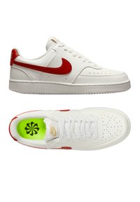 Sneakers in pelle bianca con un baffo rosso, punta tonda, dettagli perforati e una suola texturizzata. L'interno presenta una soletta verde con un design nero.