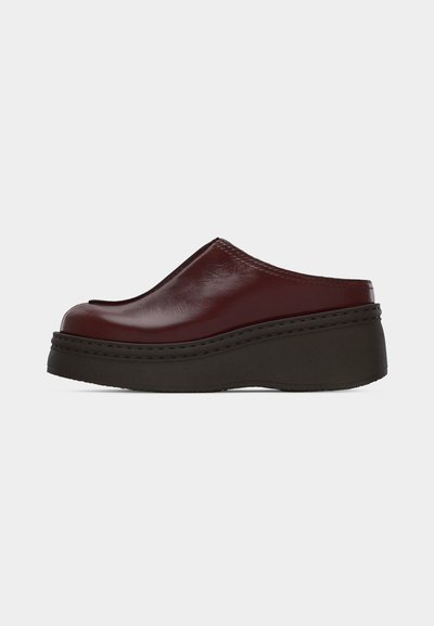 Slip-on maroon leather platform shoe with rounded toe and thick black sole, viewed from the side on a plain background.