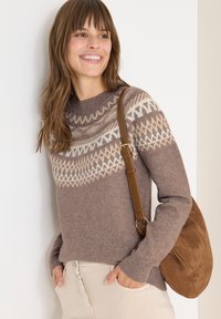 Maglione marrone lavorato a maglia con un colletto decorato in crema e beige, abbinato a pantaloni beige chiaro e una borsa a tracolla in suede marrone.