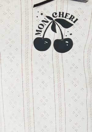 Witte stof met herhalende kleine stippen, met zwarte geprinte kersen en de tekst "MON CHERI" erboven. Gestructureerd, ribbelachtig oppervlak.