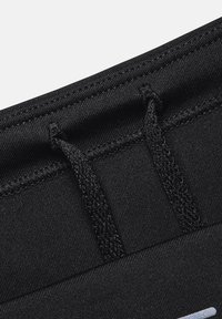 Close-up of black fabric with reinforced stitching and two black woven drawstrings threaded through eyelets.