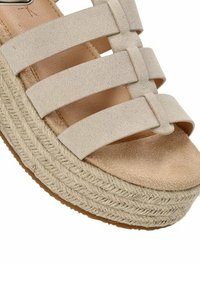 Sandaña de plataforma beige con tres correas horizontales, parte superior de ante texturizado, entresuela de yute trenzado y suela de goma.
