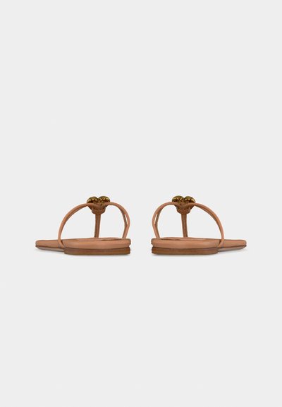 Ζευγάρι επίπεδων δερμάτινων σανδαλιών σε ανοιχτή καφέ απόχρωση με λεπτά λουράκια και μικρές μεταλλικές διακοσμητικές λεπτομέρειες, από πίσω σε απλό φόντο.