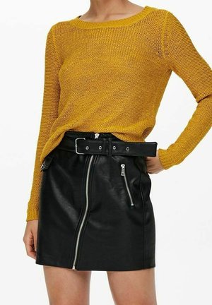 Sennepsfarvet strikket sweater med bred halsudskæring, parret med en sort læder mini-nederdel med lynlåslommer og et bælte med metalliske detaljer.