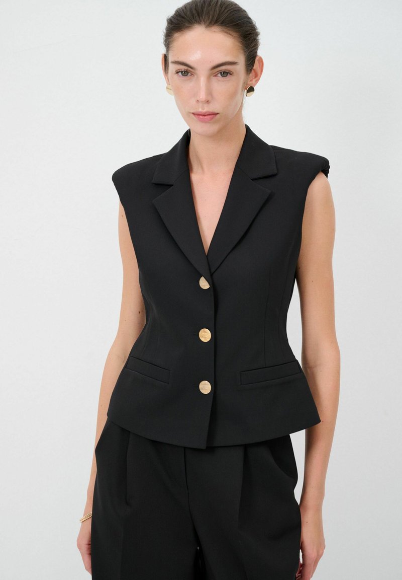 Schwarzer ärmelloser Blazer mit strukturierten Schultern, Reverskragen und goldenen Knopfverschlüssen. Verfügt über zwei Fronttaschen und eine taillierte Passform.