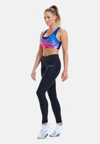 Sport bra with a gradient of blue, pink, and purple, paired with black high-waisted leggings and white athletic shoes.