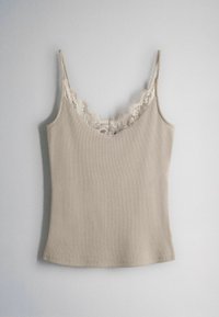 Beige ärmelloses Camisole mit Spitzenbesatz entlang des V-Ausschnitts und dünnen Schulterriemen, flach auf einem grauen Hintergrund ausgelegt.