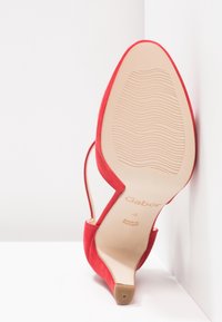 Chaussure rouge à talon haut pour femme reposant sur une surface blanche, semelle visible avec une texture antidérapante, taille 4, fabriquée au Portugal par Gabor.